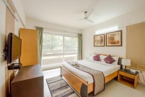 a bedroom with a bed and a tv and a window at The Altruist Business Stays Bellandur-1 in Bangalore