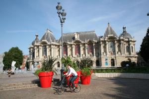 eine Person, die vor einem Gebäude Fahrrad fährt in der Unterkunft Hôtel des Reignaux in Lille