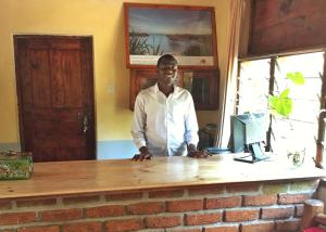 un hombre parado en un escritorio con una computadora en Outpost Lodge, en Arusha