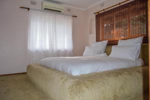 a bedroom with a large white bed with a large window at Emangunini Guest house in Richards Bay +38 photos
