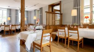 um restaurante com mesas e cadeiras brancas e janelas em Landhotel & Restaurant Walsers em Efringen-Kirchen