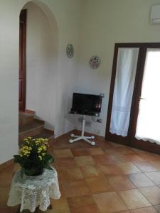 una sala de estar con TV y una mesa con un jarrón de flores en VILLA A 200 METRI DALLA SPIAGGIA, en Budoni
