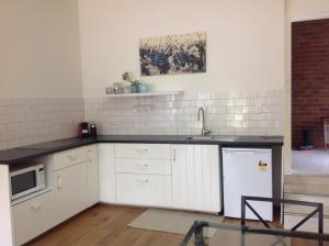 uma cozinha com armários brancos e um lavatório em Port Elliot rural retreat em Port Elliot