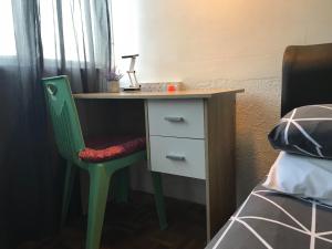 a desk with a green chair next to a bed at Check In Lodge in Kuching