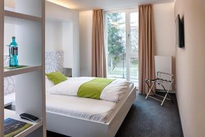 a bedroom with a bed and a large window at MARA Hotel in Ilmenau