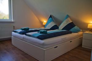 a bed with blue pillows on it in a room at Zur alten Post I in Dagebüll