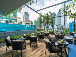 a rooftop patio with tables and chairs and a pool at Tastoria Collection Sukhumvit in Bangkok