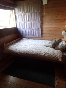 a bed in a log cabin with a window at Hodalen Fjellstue in Tolga