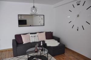 a living room with a couch and a clock on the wall at Lux Apartment in Pazardzhik