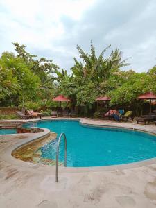 a swimming pool with chairs and umbrellas in a resort at Rini hotel in Lovina