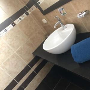 a bathroom with a white sink on a black counter at Hostal Alua Rio in Quito