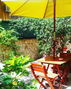 a yellow umbrella over a wooden table and a bench at Le Tare B&B in Rome