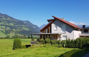 a house in a field with mountains in the background at Ferienwohnung Melanie in Hart im Zillertal