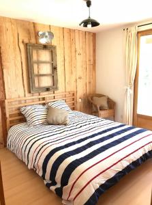 um quarto com uma cama grande e um cobertor listrado em Chambres d'Hôtes La Téouleyre em Saint-Julien-en-Born