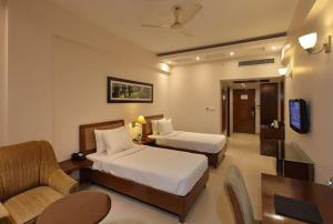 a hotel room with two beds and a couch and a tv at Lemon Tree Hotel Baddi in Baddi