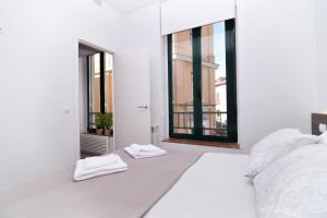 una camera da letto bianca con due asciugamani bianchi su un letto di Five Windows to La Latina by Batuecas a Madrid