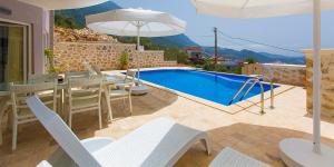 a swimming pool with a table and chairs and an umbrella at Villa Yagmur in Kalkan