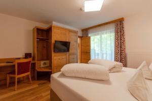 a bedroom with two beds and a desk and a television at Gasthof Weberbauer in Scheffau am Wilden Kaiser