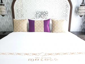 una camera da letto con un letto bianco con cuscini viola di Palette The Grand Morocc Hotel a Mae Rim