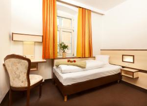 ein Schlafzimmer mit einem Bett, einem Stuhl und einem Fenster in der Unterkunft Hotel Goldene Krone Innsbruck in Innsbruck
