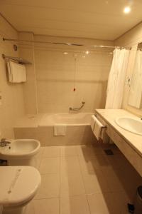 
a bathroom with a toilet, sink, and bathtub at Suite Hotel Jardins Da Ajuda in Funchal
