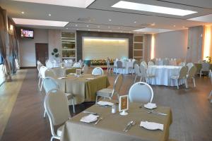 un salón de banquetes con mesas y sillas blancas y una pantalla en RPGC Garden Hotel en Ipoh