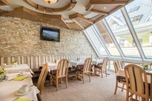 a dining room with tables and chairs and windows at Alphotel Garni Salner in Ischgl