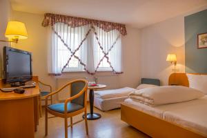 ein Hotelzimmer mit einem Bett und einem Schreibtisch mit einem TV in der Unterkunft Hotel zur Linde in Gädheim