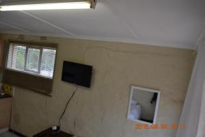 a room with a wall with a television on it at Heloise Home Stay in Oudtshoorn