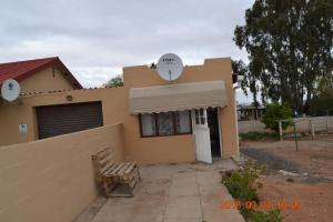 a house with a bench in front of it at Heloise Home Stay in Oudtshoorn