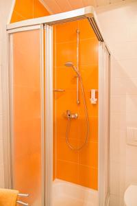 y baño con ducha y pared de color naranja. en Hotel zur Linde, en Gädheim