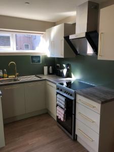 a kitchen with white cabinets and a stove top oven at Aaron Wise - 62 Plantagenet Studios in Cardiff