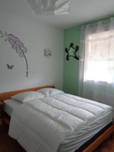Schlafzimmer mit einem weißen Bett und einem Fenster in der Unterkunft 5 Cité Creve Coeur in Manciet