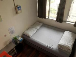 a small bed in a room with a window at Kumoji-so Hostel in Naha