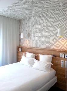 1 dormitorio con cama blanca y papel de pared geométrico en Hôtel Marin, en Laval