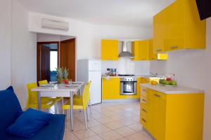 una cocina con armarios amarillos y una mesa con sillas amarillas en Residence Acquamarina, en San Benedetto del Tronto