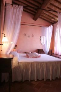 シエナにあるアグリツーリズモ レナッチーノのベッドルーム(白いカーテン付きの大型ベッド1台付)