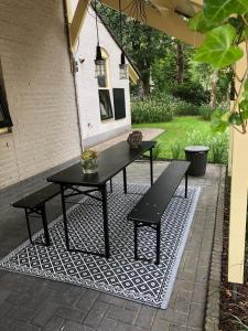 een zwarte picknicktafel en banken op een tapijt bij Huusje18 in Nunspeet
