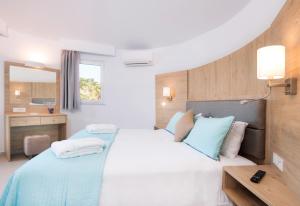 a bedroom with a large bed with blue and white pillows at Eurovillage Achilleas Hotel in Mastihari