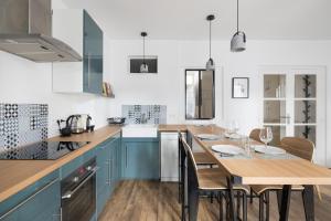 a kitchen with blue cabinets and a wooden table with chairs at L'Aurore by Cocoonr in Saint Malo