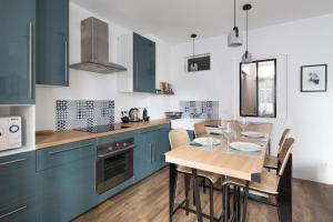 a kitchen with blue cabinets and a table with chairs at L'Aurore by Cocoonr in Saint Malo