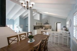 Dolphin Cottage في سيمونز تاون: مطبخ وغرفة طعام مع طاولة وكراسي خشبية