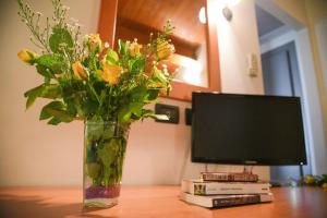 een vaas met bloemen op een tafel naast een computermonitor bij Carlo's Hotel in Castagneto Carducci