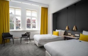 a hotel room with two beds and yellow curtains at Van der Valk Hotel Hildesheim in Hildesheim