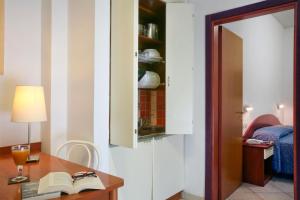 Residence I Girasoli في ريميني: غرفة بها مكتب مع مصباح وكتاب