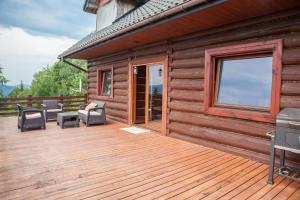 een houten terras met stoelen en een grill in een hut bij Mountain cabin in Pcim