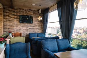 a living room with blue chairs and a tv at Triumph Hotel in Krasnodar