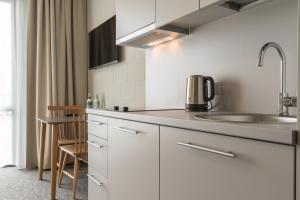 a kitchen with white cabinets and a sink at Air Hotel in Karmėlava
