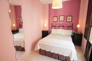 Habitación de color rosa con 2 camas y espejo. en Apartamentos La Ribera Córdoba, en Córdoba