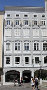 un gran edificio blanco con gente caminando delante de él en Alter Markt LOFT en Salzburgo